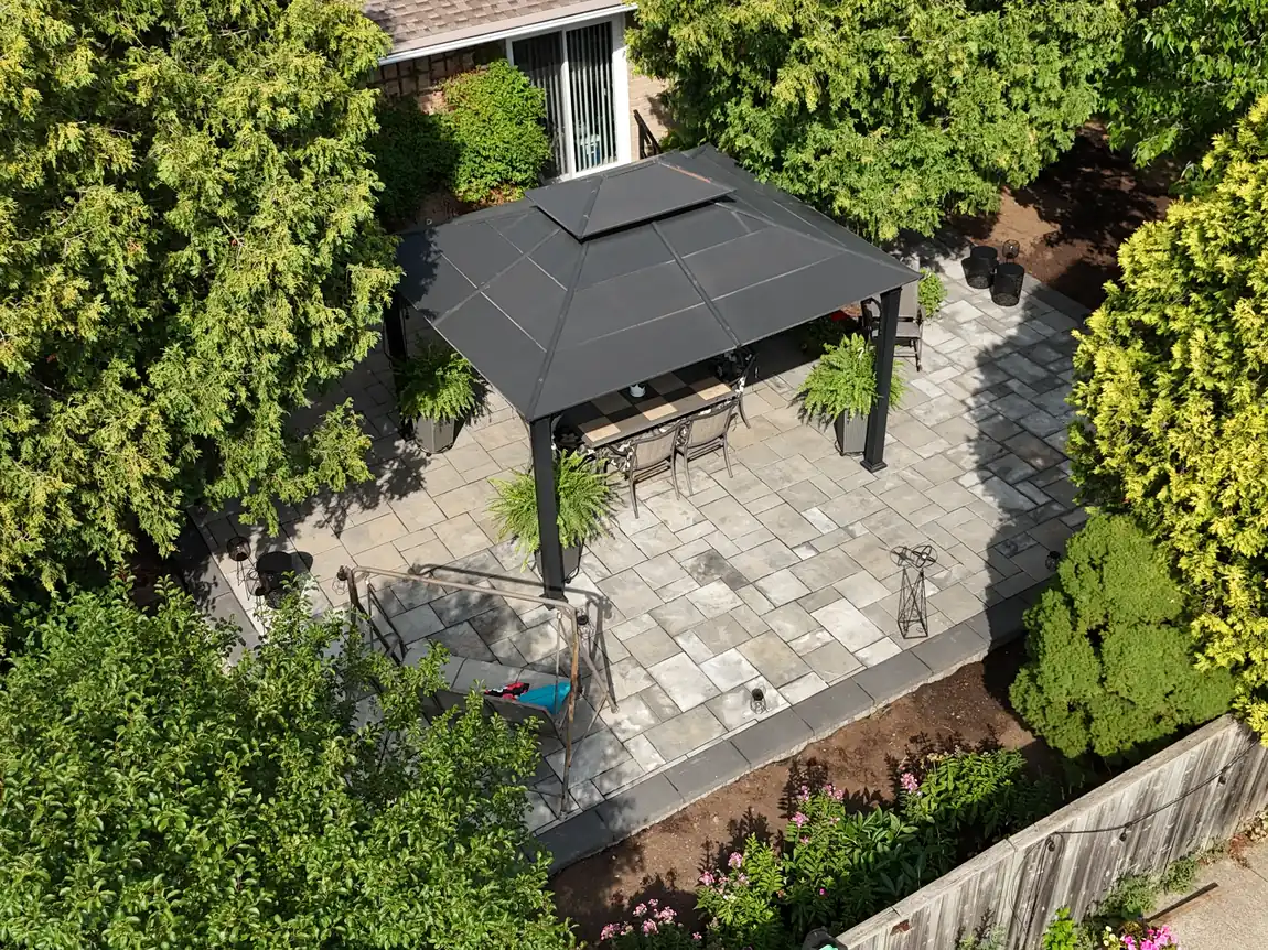 Aerial view of a new interlock patio and gazebo framed by gardens